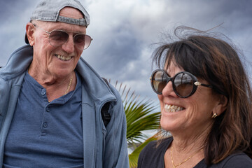 Portrait of a smiling caucasian senior couple on vacation in a cloudy day, two retired people enjoying freedom and healthy lifestyle outdoors