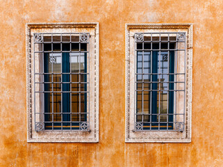 Two windows on an orange ocher colored wall of a vintage building at Mantua, Italy. Space for your text and logo.