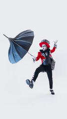 Expressive mime performer balancing with umbrella, exaggerated facial expression adding humor over...