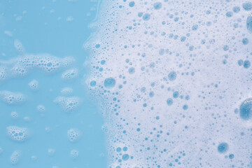 Foam on blue background. Liquid soap bubbles