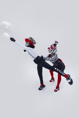 Mime artist stretching dramatically towards floating bubble as animated partner holds him back...