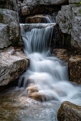 Obraz premium A small waterfall flows over rocks in a natural stream