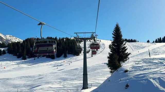 video of ski cable car lift in winter Italian Dolomites in sunny day with pines and skiers below