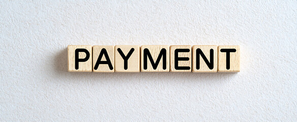 Obraz premium Wooden blocks spelling 'PAYMENT' on textured white surface. Finance, commerce, or transaction concept visualized.