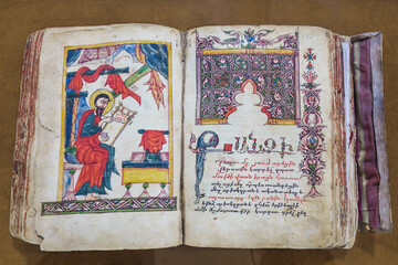 Armenian Gospel from 1490, open to a page with handwritten text. The illustration on the left shows the evangelist writing the text of the New Testament. Shot in Vank Cathedral, Isfahan, Iran