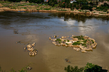 A rapid river flows through a rocks surrounded by lush greenery. 