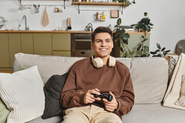 Enjoying a cozy gaming evening at home with a smile and headphones on © LIGHTFIELD STUDIOS