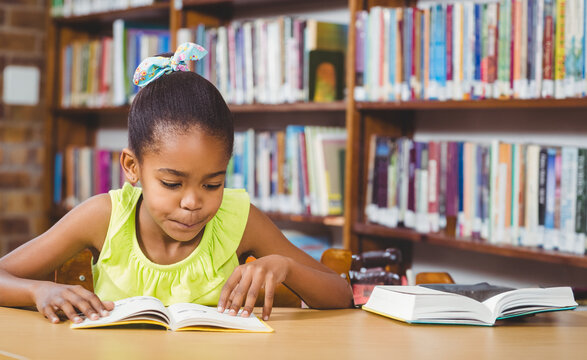 Young girl reading book in school library, concentrating on story, copy space