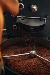 Obraz premium Vertical shot of coffee beans being roasted by professional roaster machine at factory