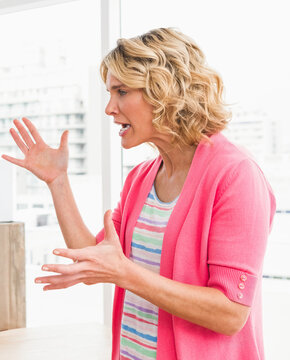 Businesswoman in pink cardigan passionately discussing ideas in modern office