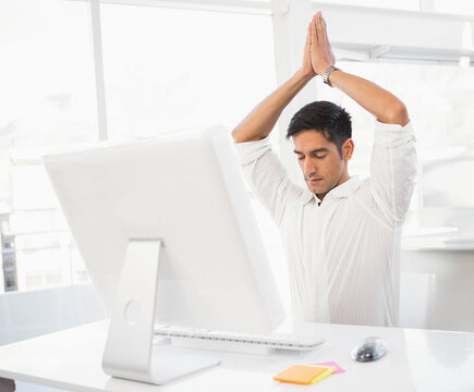 Practicing mindfulness, businessman sitting at desk in modern office environment