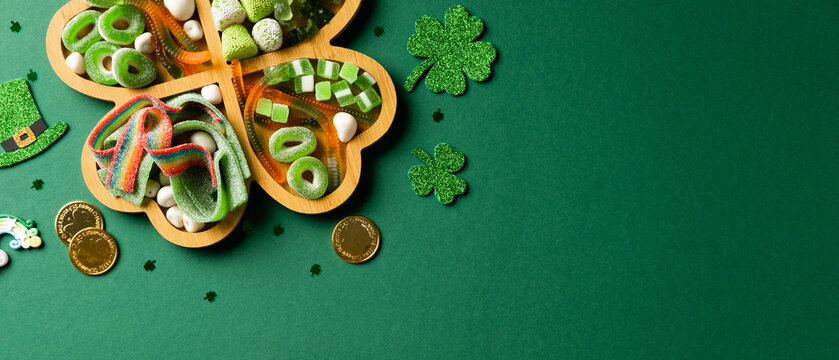 Shamrock tray with green candies, glittery shamrocks, gold coins, and a leprechaun hat on a green background