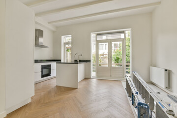 Stylish interior space featuring a kitchen and living area with natural light flooding in, highlighting wooden flooring and contemporary design.