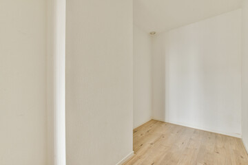 A simple, minimalist interior design showcasing a white hallway with a clean wooden floor. The light colors create a spacious and airy atmosphere.