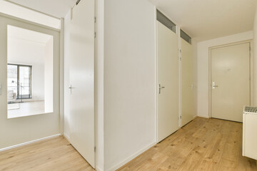 A spacious and minimalist interior hallway featuring white walls, wooden flooring, and sleek storage solutions that enhance the contemporary aesthetic of the space.