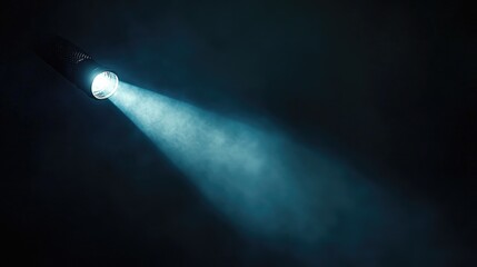 A bright, concentrated beam of light from a flashlight illuminates a dark space, creating an intense focal point in an otherwise black backdrop