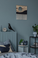 Soft blue bedroom with a woven wall hanging, minimalist nightstand, and a mix of modern and organic elements for a calming ambiance.