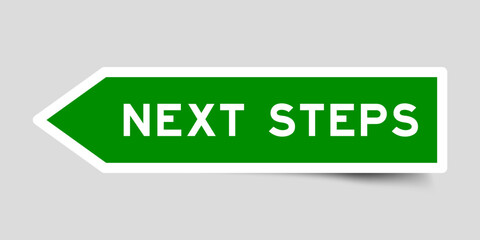 Green color arrow shape sticker label with word next steps on gray background