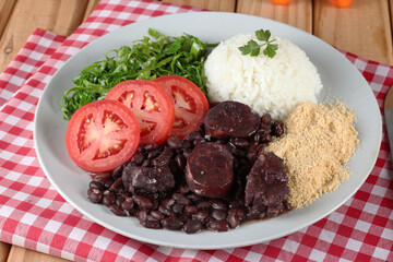 Comida tipica brasileira:  feijoada com acompanhamentos, servida no prato e na tigela