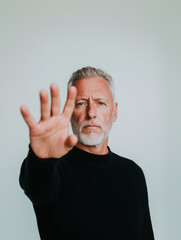 Fototapeta premium Serious mature man making a stop gesture against injustice and violence