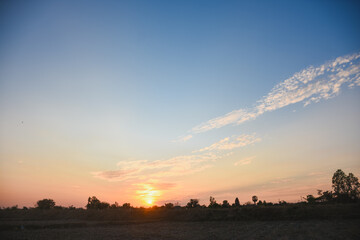 the serene and peaceful moment of sunset. The sun's warm orange and yellow hues spread across the horizon, blending seamlessly into the deep blue sky.