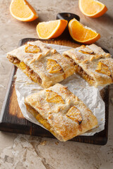 Delicious orange puff pastry pie with jam, nuts, raisins and fresh fruits close-up on wooden board on table. Vertical