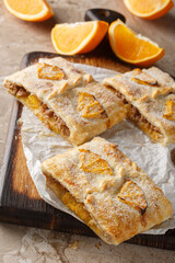 Orange strudel pie with jam, nuts, raisins and fresh fruits close-up on wooden board on table. Vertical