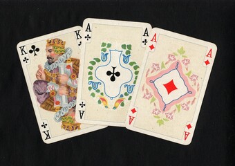 A hand of three decorative antique playing cards on a black background.