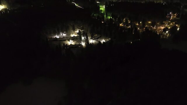 Aerial view rotating toward a illuminated cabin village, winter night in Finland
