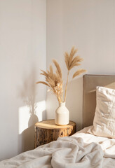 Cozy bedroom corner with dried flowers on wooden table, minimalist decor