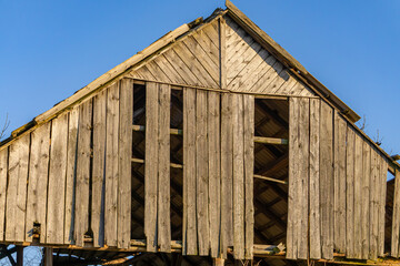 an old, dilapidated wooden barn in the countryside with holes in the wood