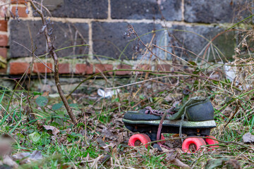 old children's roller skates abandoned in the grass next to an abandoned house