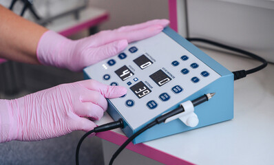 A professional technician carefully adjusting an electrolysis device in a beauty salon, ideal for themes related to hair removal, skincare, and cosmetic treatments