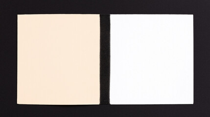 Color Contrast: Two square paper sheets, one in cream color and another one in white, against a backdrop of stark black, highlighting differences in hue. 