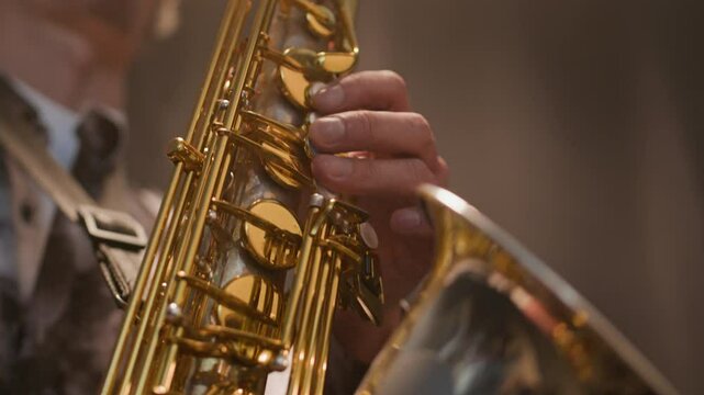 Cropped shot of hands of unrecognizable male saxophone player performing solo on his exquisite instrument creating jazz mood