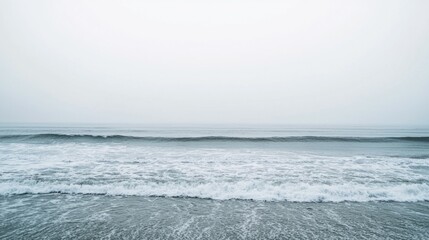 Fototapeta premium Serene Ocean Waves Against Soft Gray Sky and Calm Water Surface