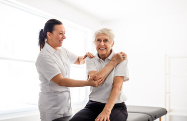 physiotherapist helping senior woman in clinic. Elderly woman undergoing physiotherapy treatment...