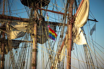 A rainbow flag being displayed on a sailboat.