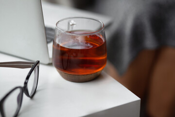 close-up of the cup of tea and glasses aginst the woman