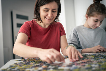 Fototapeta premium Mother And Daughters Assembling Puzzles On A Table As The Family Spends Time Together