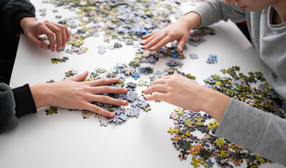 Girls Putting Puzzle Pieces Together On The Table A Hobby For The Whole Family