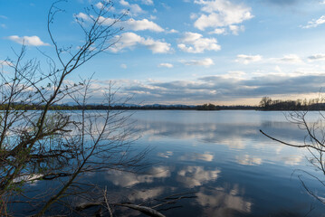 Pond with tree branches above and hills on the background during early springtime evening