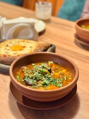 national Uzbek dish Shurpa soup in a clay plate on a wooden table