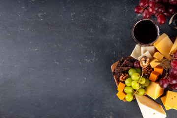 Tasty delicious cheese and dried sausage appetizers board, with wine, nuts, grapes fruits,...
