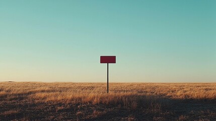 Minimalistic landscape with a blank red signpost in a golden field under a clear blue sky, representing emptiness and potential for creativity