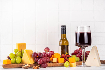 Tasty delicious cheese and dried sausage appetizers board, with wine, nuts, grapes fruits, antipasto brunch snack, copy space