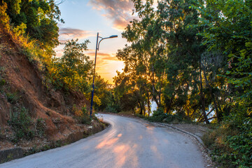 A mountainous dirt road overlooking the sea, a bumpy road with red soil amidst forest trees and blue sky facing the sea with sunset, wandering among the beautiful green nature in Jijel Algeria, Africa