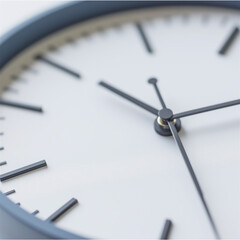 A close-up of a modern clock with a focus on the hands and the movement of time. The clock on a simple background represents the continuity of time and precision.
