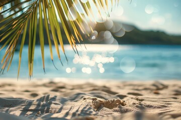 Obraz premium Summer beach sand and palm leaf bokeh light background.
