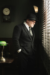 Portrait of detective is looking into the window in his vintage office